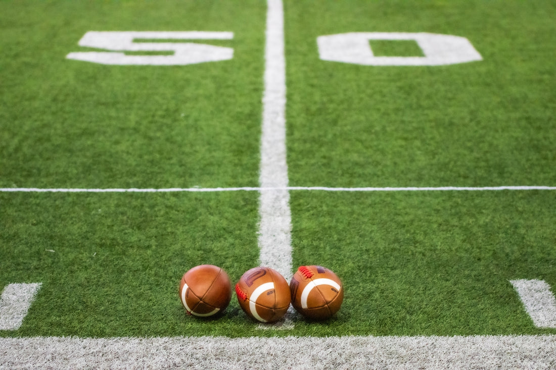 Three footballs sitting on a football field