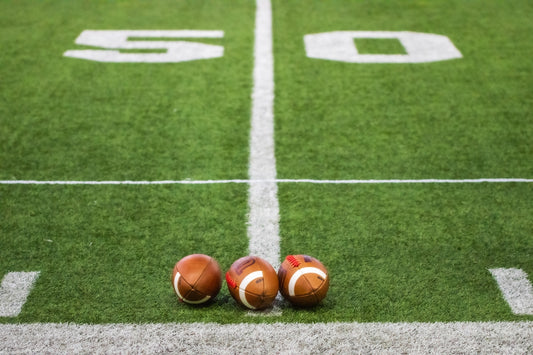 Three footballs sitting on a football field